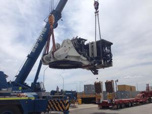 Big Construction Vehicle being moved by crane for road freight as part of freight forwarding process